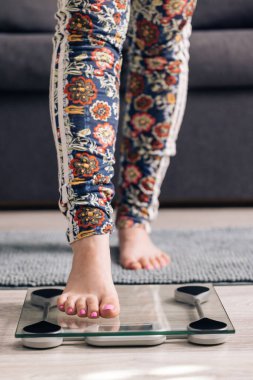Girl Legs Step On Bathroom Scale. Woman On Scales Measure Weight. Human Barefoot Measuring Body Fat Overweight. Slim Woman Checking BMI Weight Loss. Diet Female Feet Standing Weighing Scales On Room
