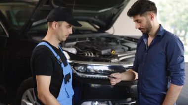 Male client giving car key to auto mechanic in repair shop. Car repair. Man owner of the auto gives the keys to the car repairman. Vehicle breaks down on the road.