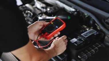 Check battery voltage with electric multimeter. Car starter battery. Professional mechanic is working in car service. Good, electrician, electricity, battery charged fully
