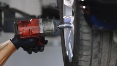 Assembly or dismantling of the wheels in the workshop. repair and maintenance of the car in service. Car mechanic replacing car wheel of lifted automobile at repair service station.