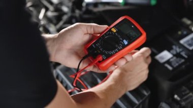 Man using multimeter to measure the voltage of the batteries. Mechanic doing car inspection, he is testing car battery with tester. Check battery voltage with electric multimeter.