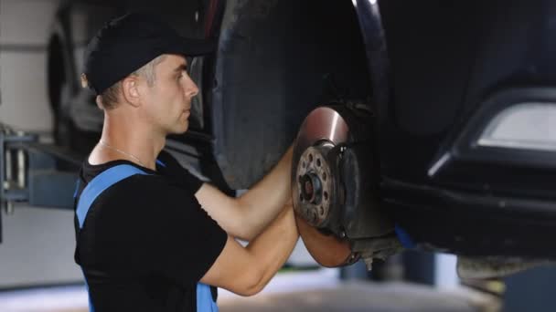 Car Mechanic Blue Overalls Replacing Car Wheel Brake Shoes Lifted — Stockvideo