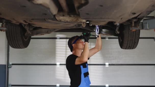 Young Caucasian Man Gloves Blue Coveralls Tightens Bolt Car Using — 图库视频影像