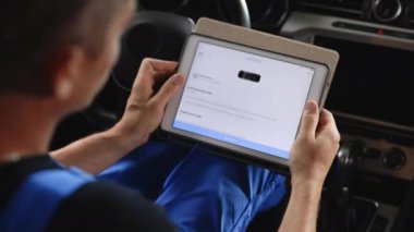 Automotive mechanic running diagnostics software on tablet. Unrecognizable vehicle service manager worker work in mechanics garage, check and maintenance to repair the engine car in workshop.