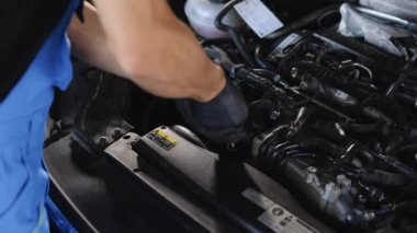 The car mechanic is checking the engine oil level. Overheating of car engine. Motor with open hood. Checking the engine oil car maintenance Remove the dipstick to view the engine oil level.