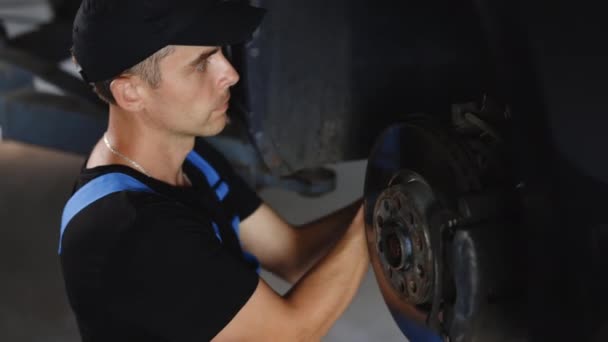 Car Mechanic Blue Overalls Cap Replacing Car Wheel Brake Shoes — Vídeo de Stock