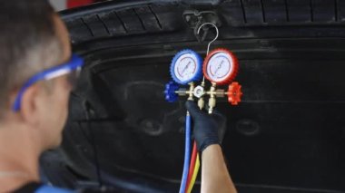 Car lies system of manometers for refueling air conditioner. Car refilling air condition in air shop. The hands of the master unscrew the protective cap of the air conditioner.