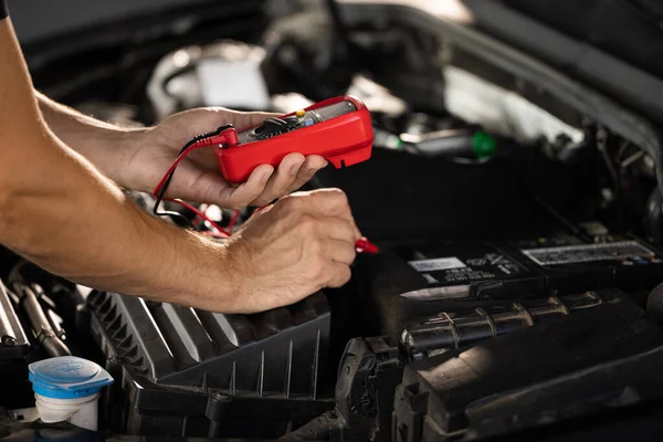 Check battery voltage with electric multimeter. Car starter battery. Professional mechanic is working in car service. Good, electrician, electricity, battery charged fully