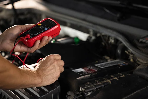 Check battery voltage with electric multimeter. Man using multimeter to measure the voltage of the batteries. Mechanic doing car inspection, he is testing car battery with tester.