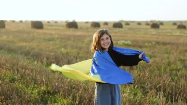 Tarlada Ukrayna bayrağı taşıyan bir çocuk portresi. Ulusal bayrak sallayan küçük kız barış için dua ediyor. Bağımsızlık Günü 'nü kutlayan mutlu çocuk. Ukrayna için dua et..