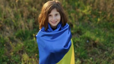 Tarlada Ukrayna bayrağı taşıyan bir çocuk portresi. Ulusal bayrak sallayan küçük kız barış için dua ediyor. Bağımsızlık Günü 'nü kutlayan mutlu çocuk. Ukrayna için dua et..