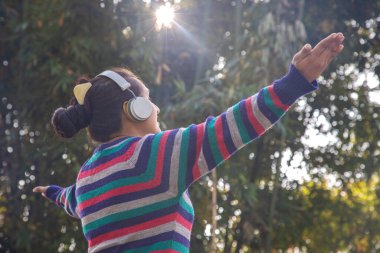 Indian girl wearing wireless headphones enjoying listening music outdoor clipart