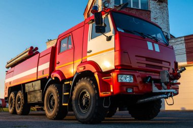 İtfaiye istasyonunun yanına park etmiş kırmızı itfaiye aracı.