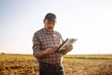 Çiftçi bazı haritaları izliyor ve toprağın kalitesini kontrol ediyor. Tarım, bahçıvanlık, iş veya ekoloji kavramı.