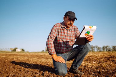 Çiftçi bazı haritaları izliyor ve toprağın kalitesini kontrol ediyor. Tarım, bahçıvanlık, iş veya ekoloji kavramı.