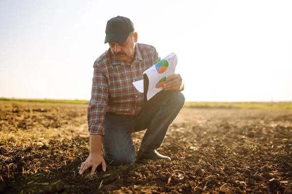 Çiftçi bazı haritaları izliyor ve toprağın kalitesini kontrol ediyor. Tarım, bahçıvanlık, iş veya ekoloji kavramı.