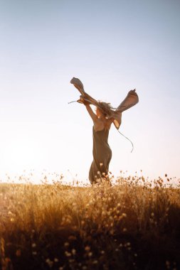 Kıvırcık kadın denizin üstünde bir kayanın kenarında poz veriyor, mavi gökyüzü ve deniz altyapısı ile. Sonbahar tarzı. Seyahat ve macera.