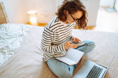 Evde çalışan bir kadın. Sosyal ağda arkadaşlarıyla sohbet ediyor, internetten alışveriş yapıyor, telefon kullanarak e-posta yazıyor. Sosyal uzaklık. Kişisel İzolasyon.