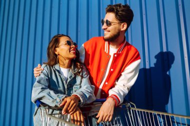 Pozitif erkek ve kadın eğleniyor ve alışveriş arabasına biniyor. İki genç arkadaş alışverişe gidiyor. Kara Cuma. Tüketim, satış, indirimler, yaşam tarzı konsepti.