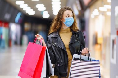 Alışverişten sonra koruyucu maskeli şık bir kadın. Kara Cuma. Tüketim, alım, satış, yaşam tarzı, turizm konsepti.