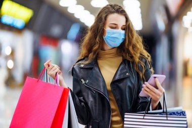 Alışverişten sonra koruyucu maskeli şık bir kadın. Kara Cuma. Tüketim, alım, satış, yaşam tarzı, turizm konsepti.