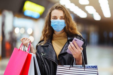 Alışverişten sonra koruyucu maskeli şık bir kadın. Kara Cuma. Tüketim, alım, satış, yaşam tarzı, turizm konsepti.