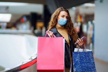 Alışverişten sonra koruyucu maskeli şık bir kadın. Kara Cuma. Tüketim, alım, satış, yaşam tarzı, turizm konsepti.