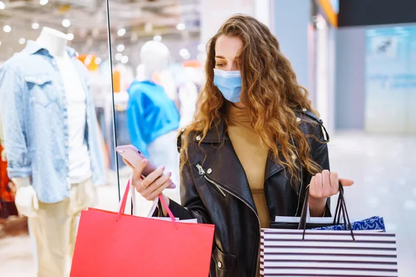 Stylish woman in protective mask after shopping. Black friday. Consumerism, purchases, sale, lifestyle, tourism concept.