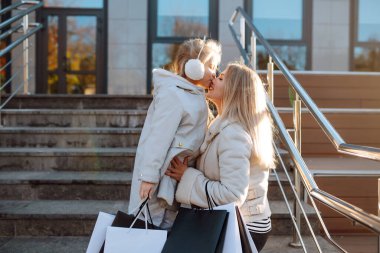 Alışveriş yaptıktan sonra alışveriş torbalarıyla gezen genç bir anne ve sevimli bir çocuk. Kara Cuma. Tüketim, alım, satış, yaşam tarzı, turizm.