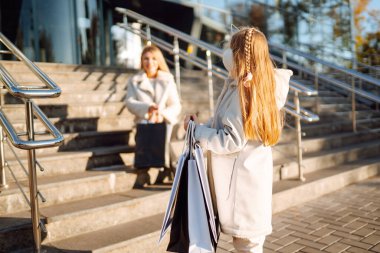 Alışveriş yaptıktan sonra alışveriş torbalarıyla gezen genç bir anne ve sevimli bir çocuk. Kara Cuma. Tüketim, alım, satış, yaşam tarzı, turizm.