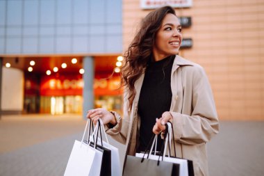 Alışveriş merkezinin yakınında torbaları olan Afro-Amerikalı bir kadın. Kara Cuma. Tüketim, satış, indirimler, yaşam tarzı konsepti.