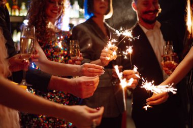 Parıldayan maytaplar ellerinde. Partide arkadaşlarıyla kış tatilini kutlamak için havai fişek oynuyorlar. Sihirli yeni yıl, Noel.