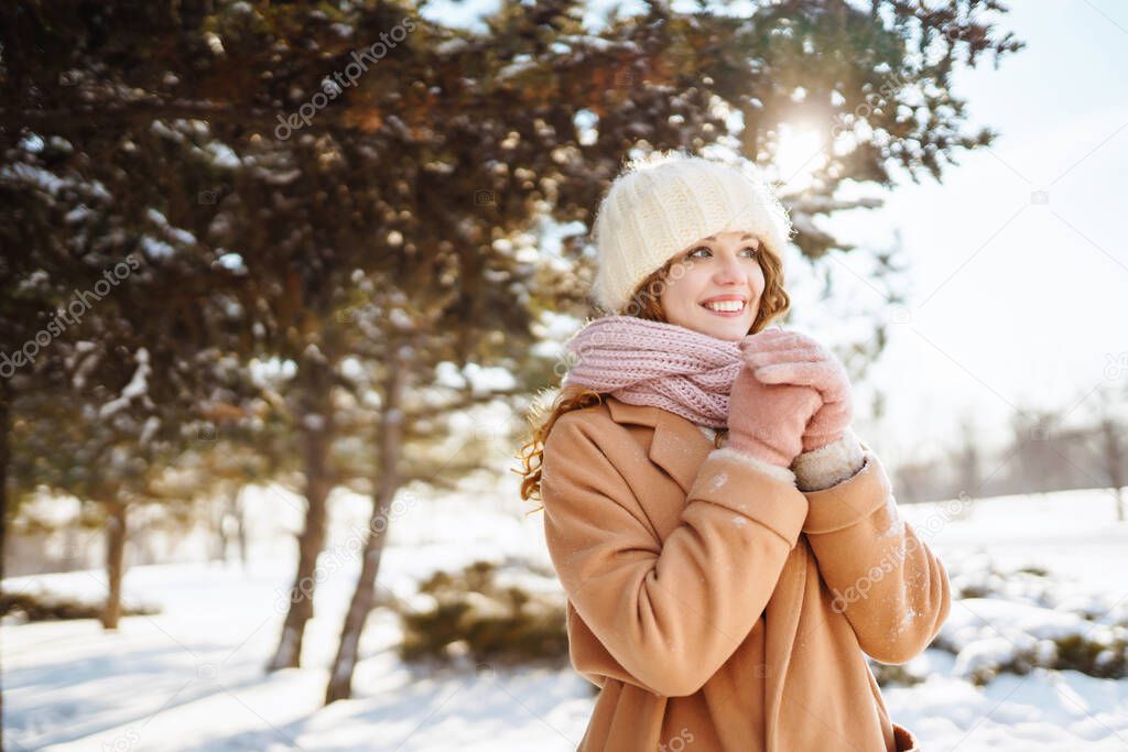 Happy woman walking in the snowy winter day outdoor. Winter fashion, holidays, rest, travel concept.