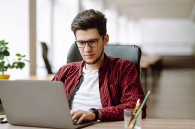 Dizüstü bilgisayarda çalışan genç bir adam. Eğitim ve online çalışma. Bağımsız, teknoloji, uzak iş ve yaşam tarzı konsepti.