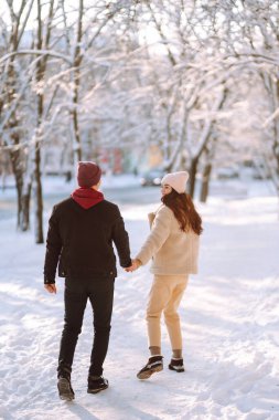 Kış ormanlarında yürüyen sevgi dolu genç bir çift. Genç bir adam ve bir kadın dışarıda sarılıp öpüşüyor. Tatiller, mevsimler, aşk ve eğlence kavramı.