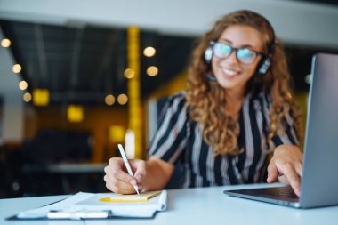 Telsizli genç bir kadın çağrı merkezinde çalışıyor. Öğrenci, öğretmen ve iş kadını bilgisayardan kablosuz kulaklık takıyor..