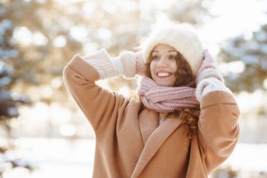 Karlı ormanda kışın giydiği kıyafetlerle yürüyen mutlu bir kadın. Doğa, tatiller, dinlenme, seyahat konsepti.