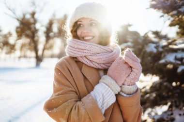 Karlı ormanda kışın giydiği kıyafetlerle yürüyen mutlu bir kadın. Doğa, tatiller, dinlenme, seyahat konsepti.