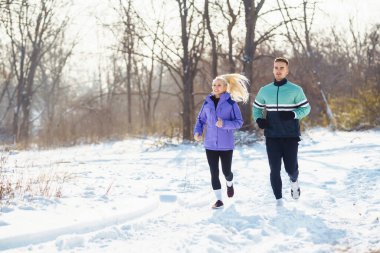 Genç çiftler kış sabahı karlı ormanda egzersiz yapıyor. Sağlıklı fitness yaşam tarzı. Spor, Aktif Yaşam.