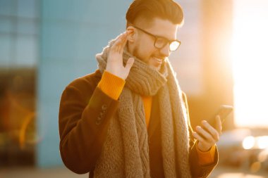 Hat bağlantısı. Kışlık giysiler içindeki genç adam sokakta yürüyor, telefonuna bakıyor ve mesaj yolluyor. İş konsepti