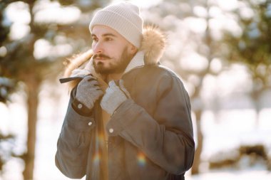 Karlı kış ormanlarında genç bir adamın portresi. Sezon, Noel, seyahat ve insanlar konsepti.