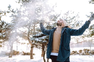 Karlı kış ormanlarında genç bir adamın portresi. Sezon, Noel, seyahat ve insanlar konsepti.