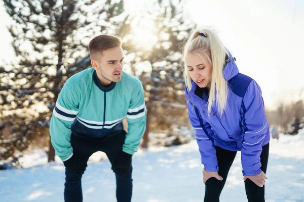 穿着运动服的年轻夫妇在雪地的森林里晨练 运动和健康生活方式概念 — 图库照片