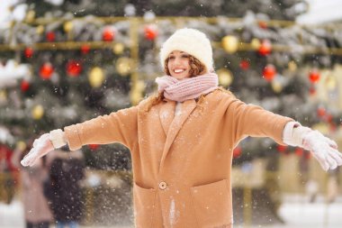 Kış tarzı giysiler içinde mutlu bir kadın çelenk ışıklarına karşı. Kış modası, tatil konsepti.