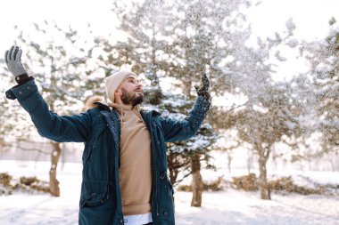 Handsome bearded young  man standing outdoors fur hood in winter season forest. Season holiday leisure. Nature.