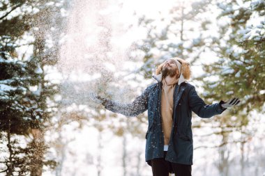 Handsome bearded young  man standing outdoors fur hood in winter season forest. Season holiday leisure. Nature.