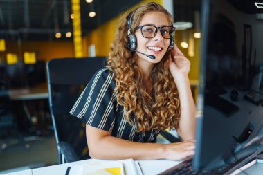 Call center agent with headset working on support hotline in modern office. Video conference.  nline training.
