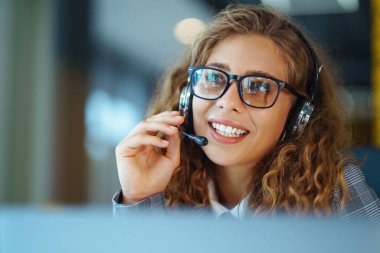 Call center agent with headset working on support hotline in modern office. Video conference.  nline training.
