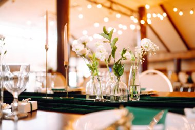 Floral decorations on the banquet table in the restaurant. The work of professional florists in emerald color. Wedding, birthday, party, event concept.