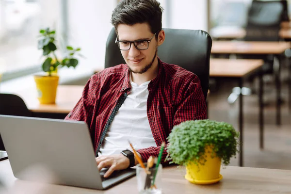 Eğitim ve online çalışma. Dizüstü bilgisayarda çalışan gözlüklü genç adam. Teknoloji, serbest çalışma, çevrimiçi kurs, uzaktan çalışma ve yaşam tarzı konsepti.